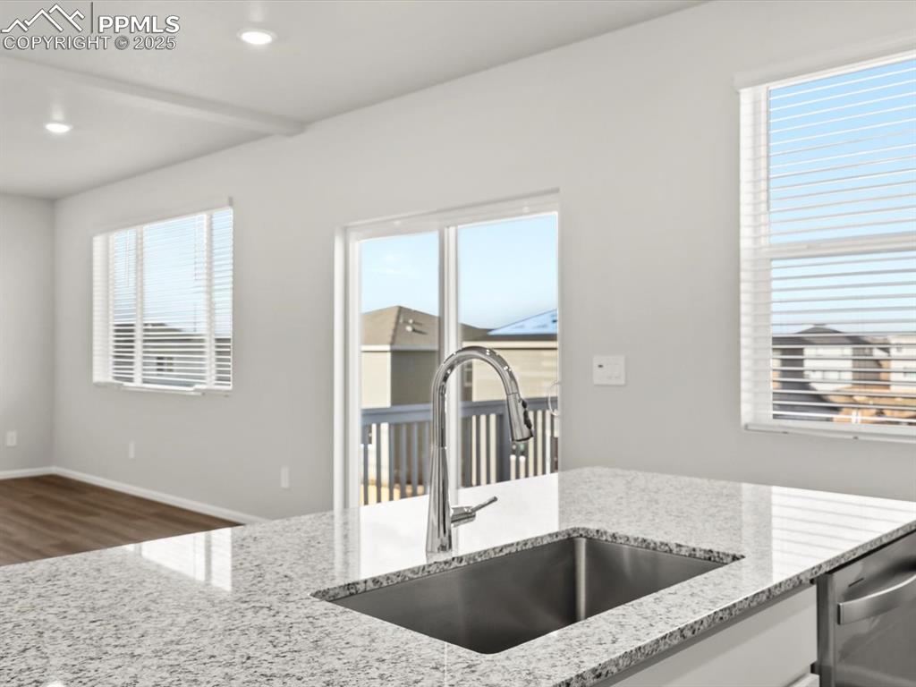 Image 4 of 26: Kitchen featuring light stone counters, stainless steel dishwasher, dark wo
