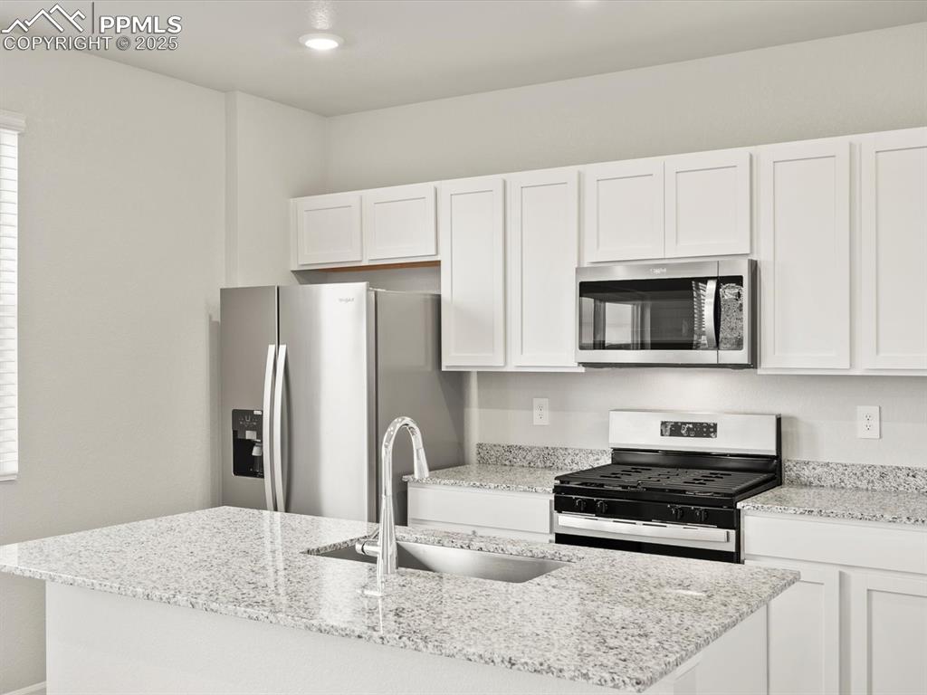 Image 5 of 26: Kitchen featuring appliances with stainless steel finishes, white cabinetry