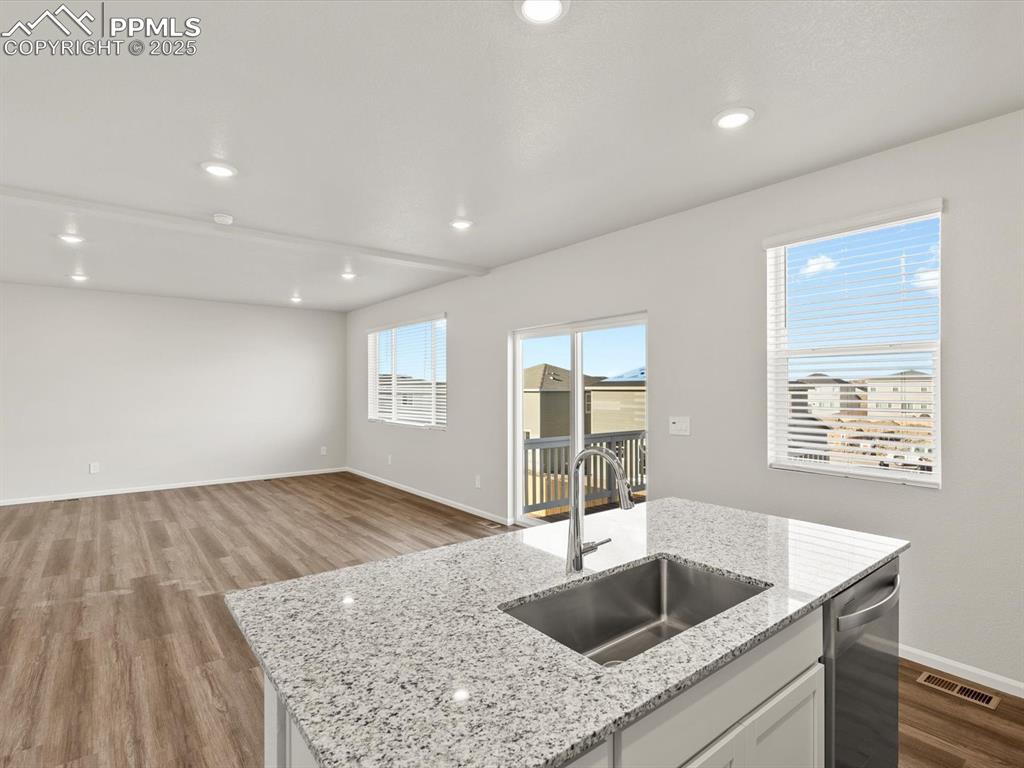 Image 6 of 26: Kitchen with white cabinetry, an island with sink, dark wood-style flooring