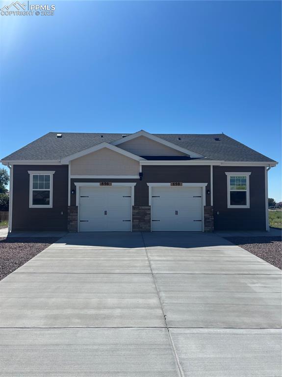 Caption: View of front facade with concrete driveway, stone siding, and a garage