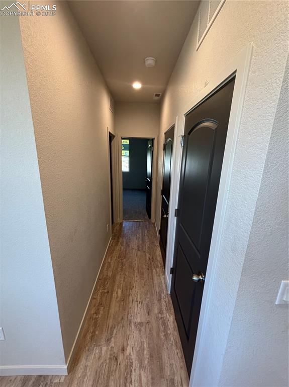 Image 11 of 13: Corridor with a textured wall and dark wood finished floors