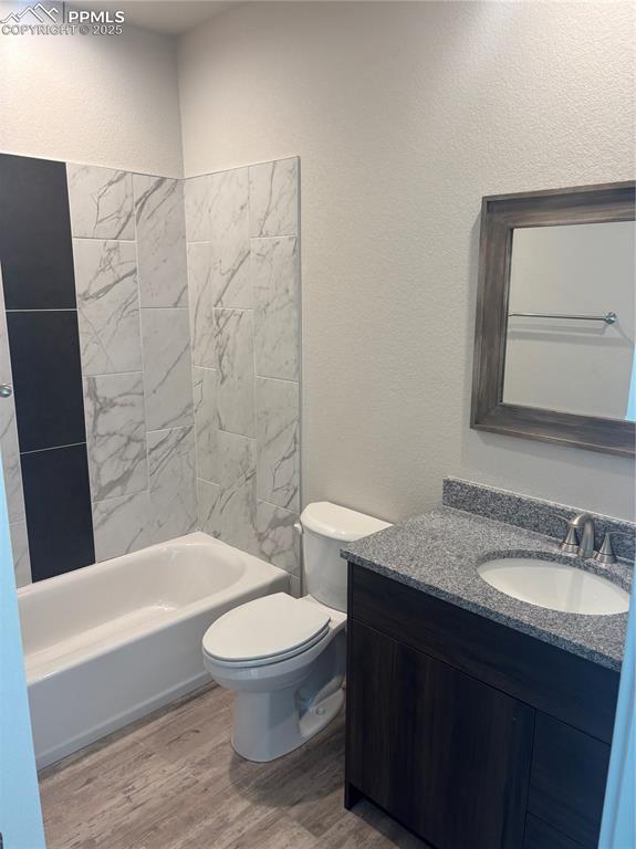 Image 12 of 13: Bathroom with a textured wall, light wood finished floors, vanity, and show