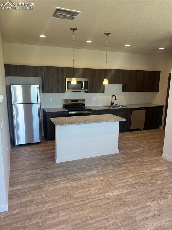 Image 5 of 13: Kitchen with dark brown cabinetry, fridge, stainless steel electric range o