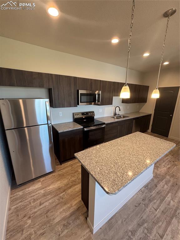 Image 6 of 13: Kitchen featuring dark brown cabinetry, refrigerator, stainless steel range