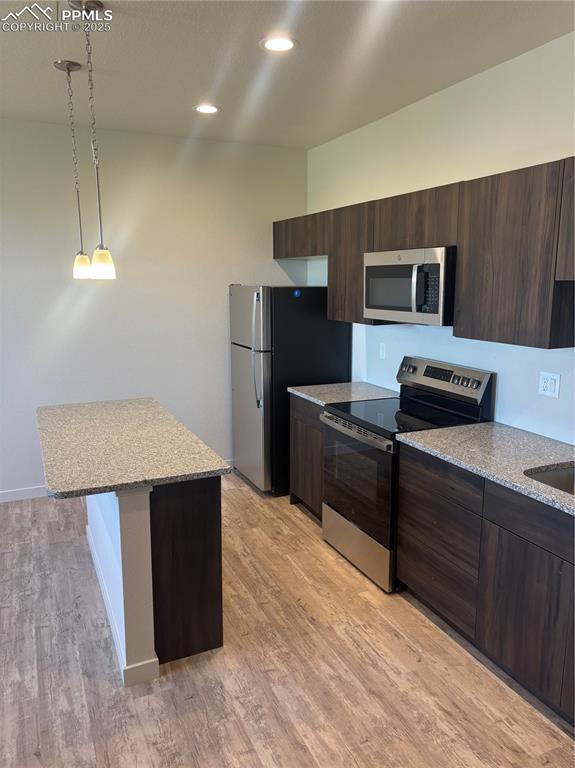 Image 7 of 13: Kitchen with stainless steel range oven, light stone counters, dark brown c