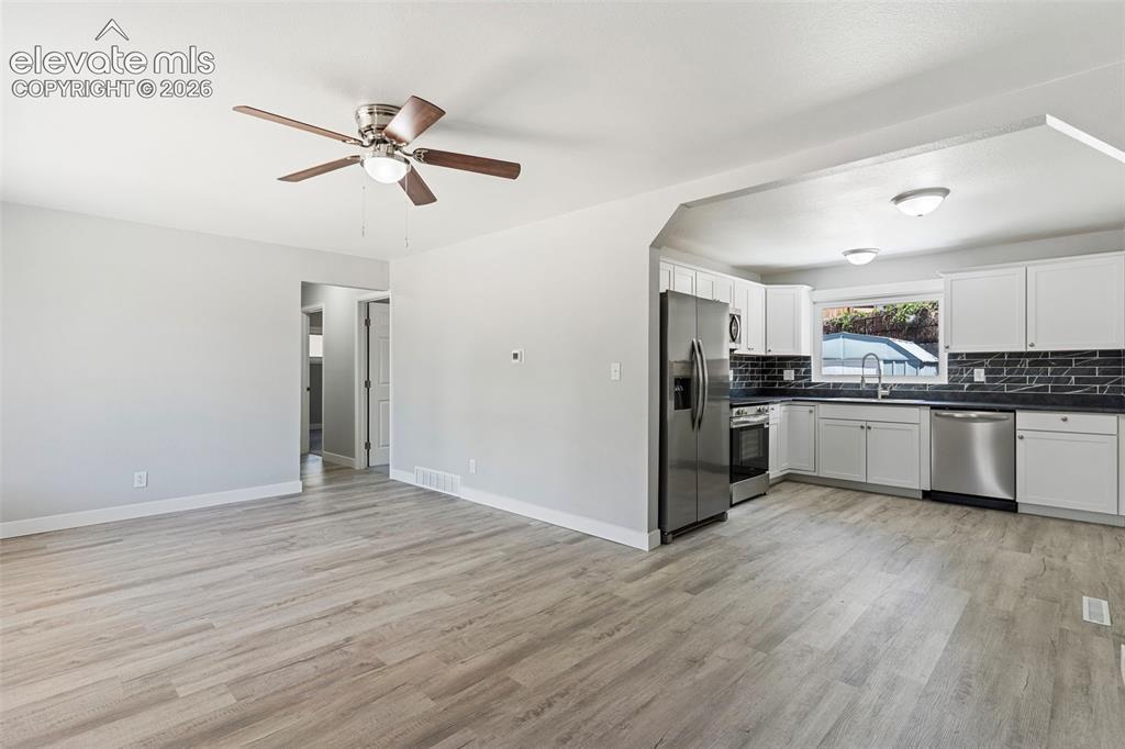 Image 15 of 33: Wood-finish flooring throughout, ceiling fan with integrated lighting, whit