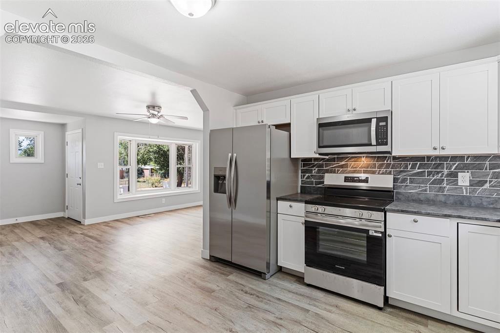 Image 17 of 33: Kitchen featuring white cabinetry, stainless steel appliances, dark counter