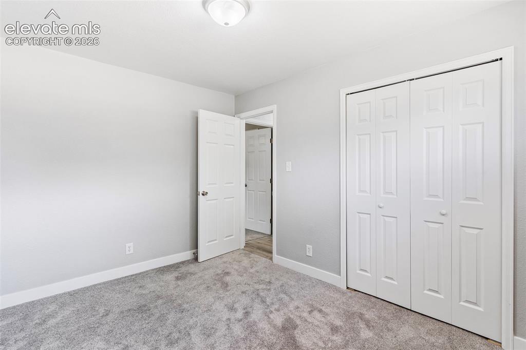Image 22 of 33: Light gray wall finish, recessed lighting, carpet flooring, white paneled d