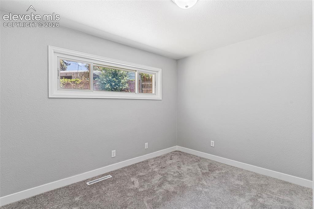 Image 28 of 33: Neutral gray wall finish, white trim, textured carpeting, and a white-frame
