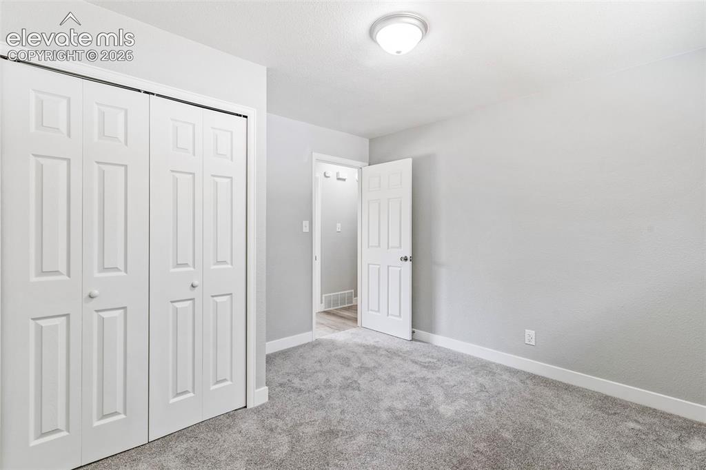 Image 29 of 33: Gray wall-to-wall carpeting, white baseboards, and a white ceiling with a f
