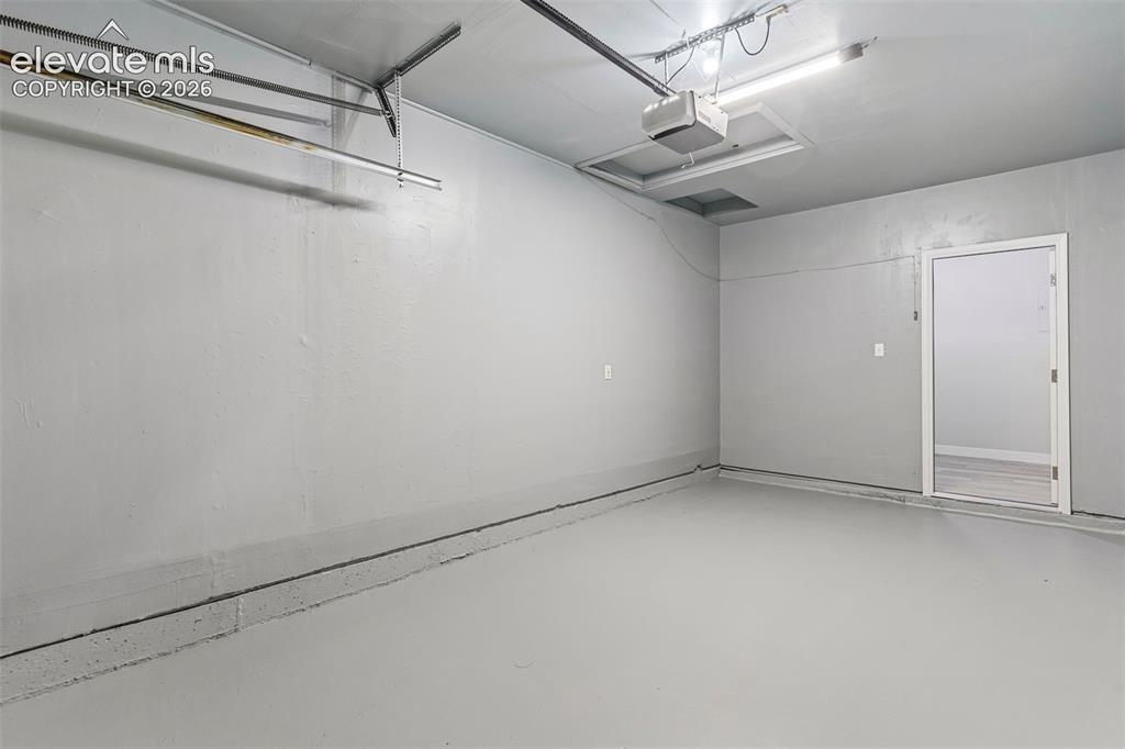 Image 30 of 33: Spacious garage with painted concrete flooring, recessed lighting, and an i