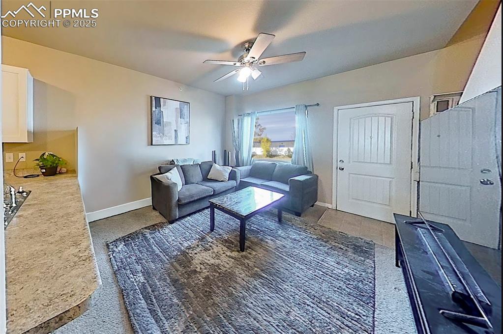 Image 12 of 29: Living area with ceiling fan and light speckled floor