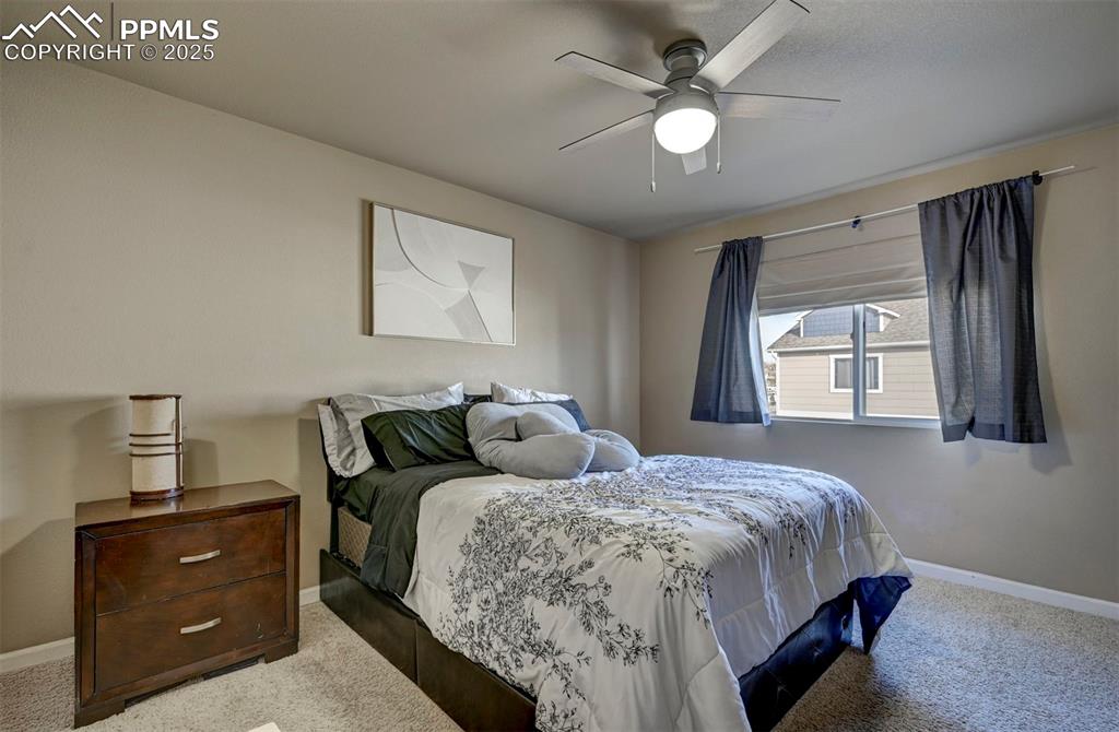 Image 14 of 29: Bedroom with light colored carpet and a ceiling fan