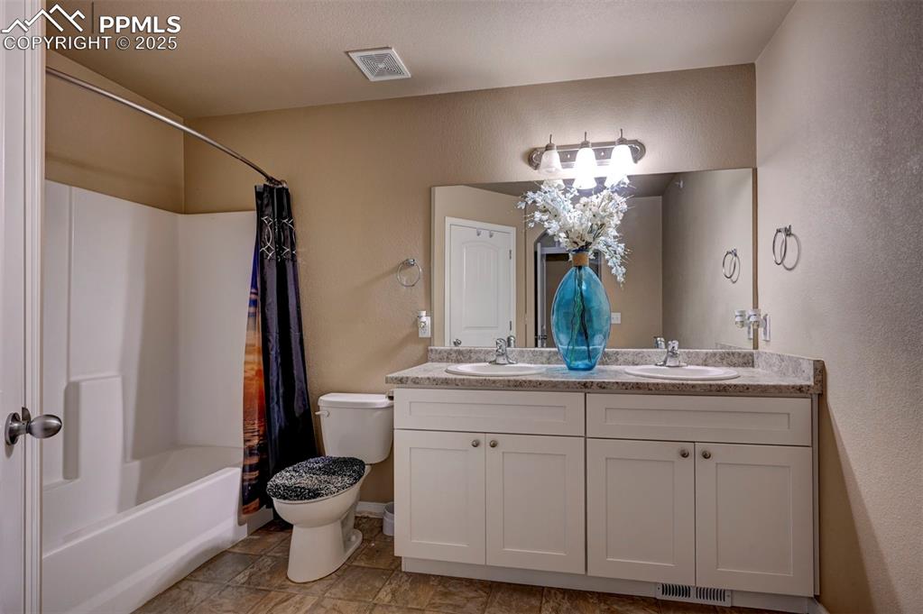 Image 17 of 29: Full bathroom with a textured wall, double vanity, and shower / bathtub com