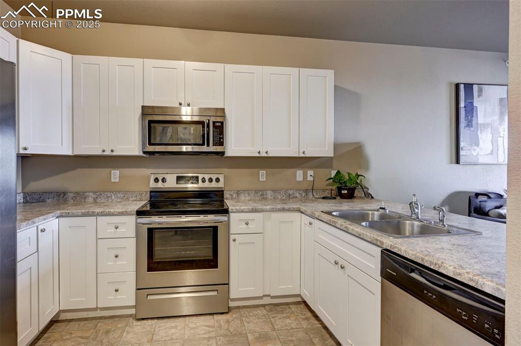 Image 8 of 29: Kitchen featuring stainless steel appliances, white cabinetry, and light co