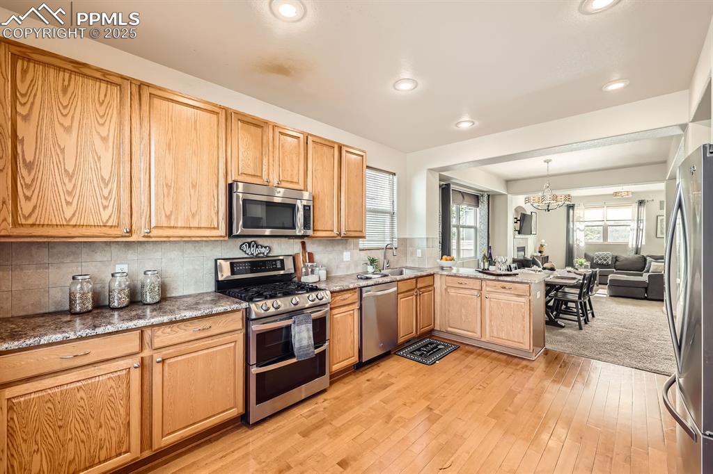 Image 11 of 39: Kitchen with stainless steel appliances, decorative backsplash, a peninsula