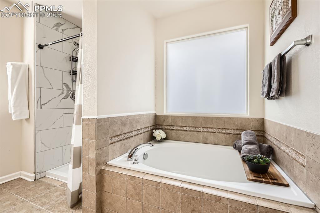 Image 18 of 39: Full bathroom featuring a shower stall, a bath, and tile patterned floors