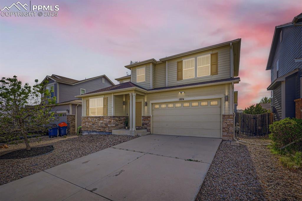 Image 2 of 39: View of front facade with stone siding, driveway, and an attached garage