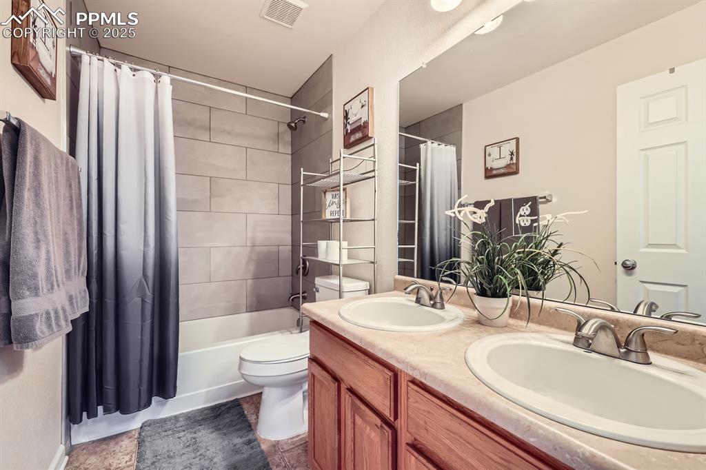 Image 21 of 39: Bathroom with shower / tub combo with curtain and double vanity