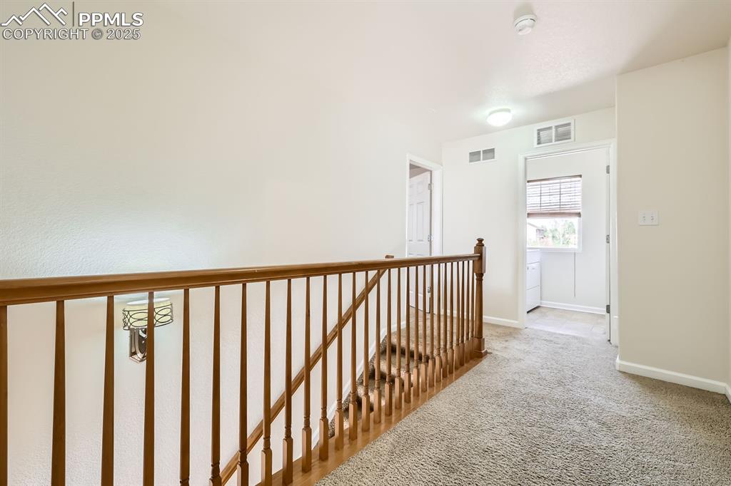 Image 26 of 39: Corridor with an upstairs landing and light carpet