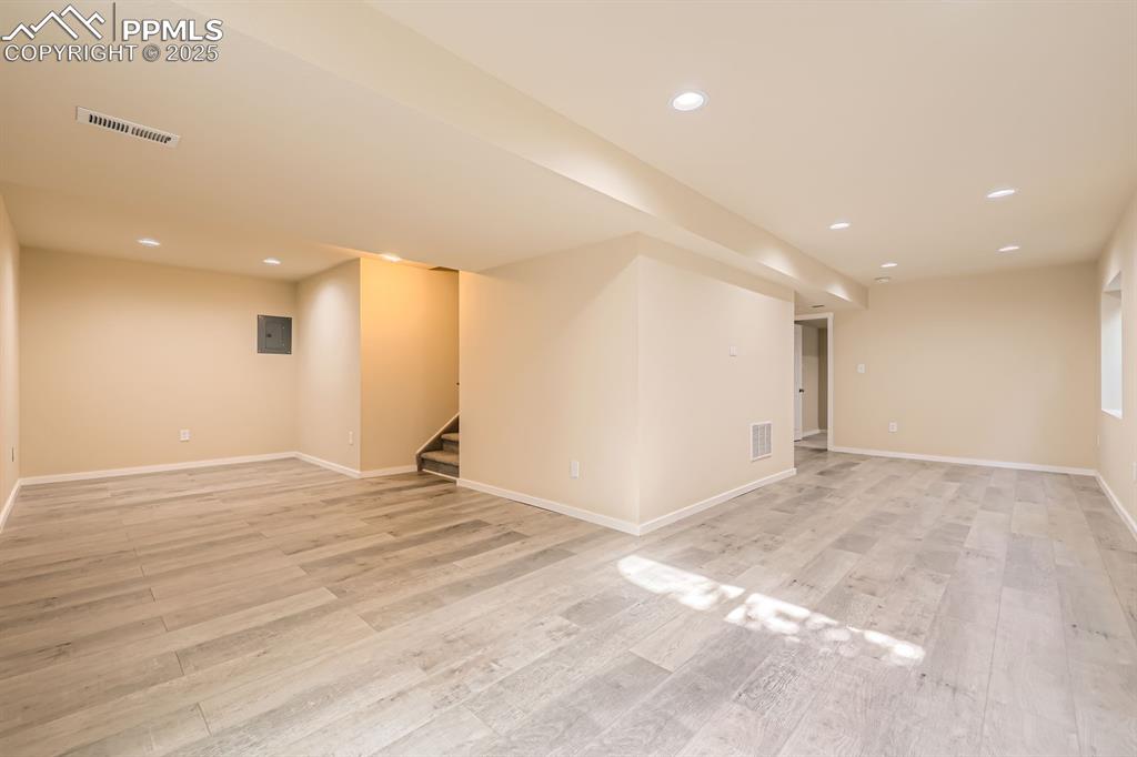 Image 30 of 39: Finished below grade area featuring recessed lighting, stairway, light wood