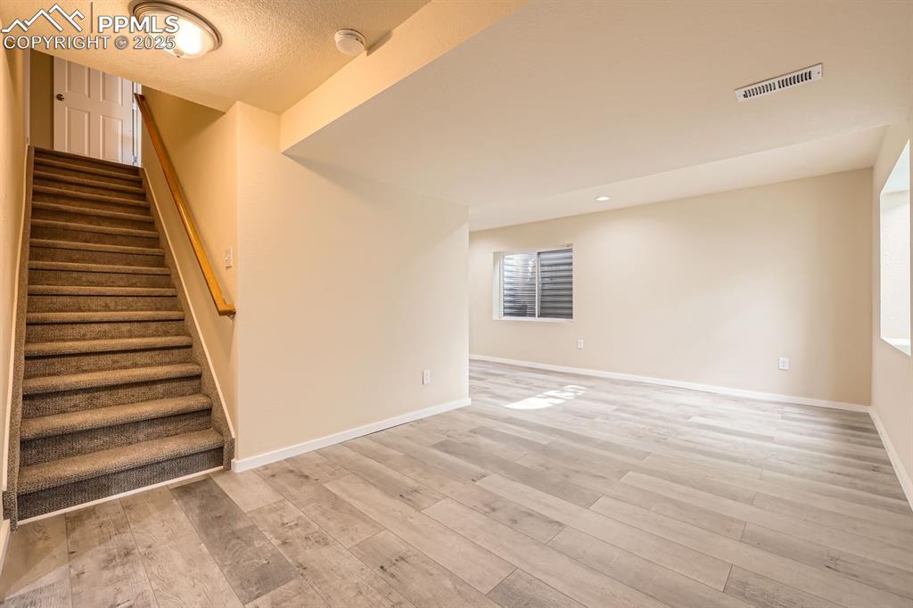 Image 31 of 39: Stairs with wood finished floors and recessed lighting