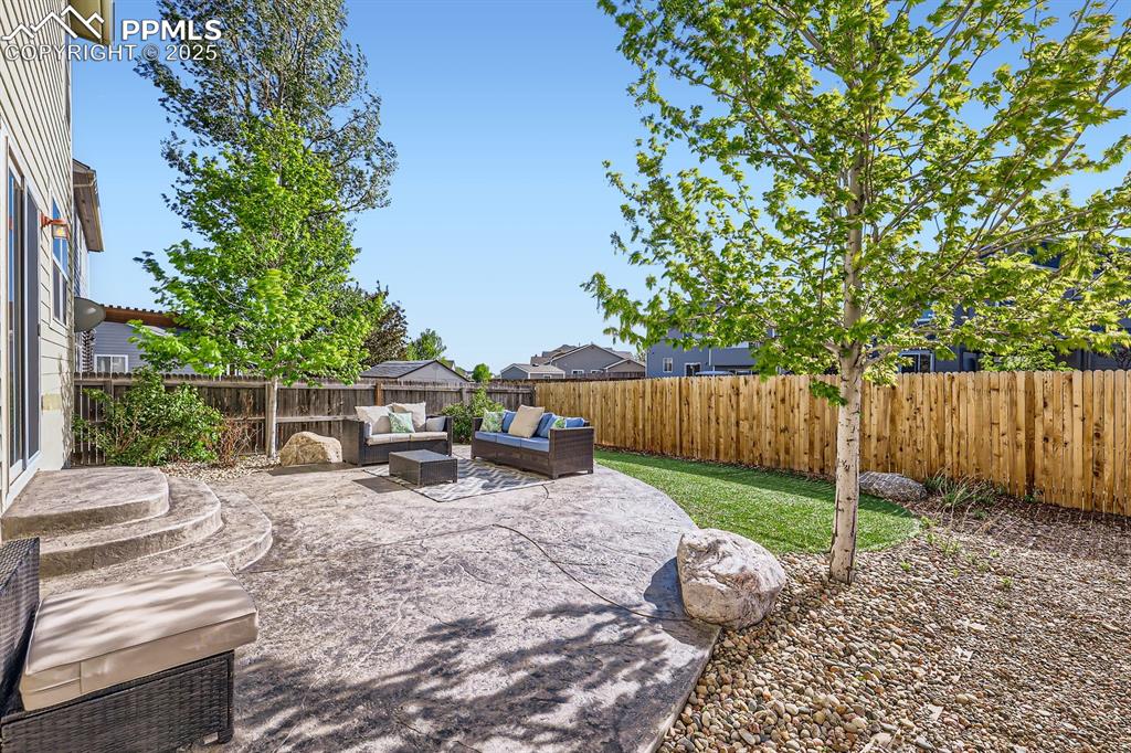Image 38 of 39: Fenced backyard with a patio area and an outdoor hangout area