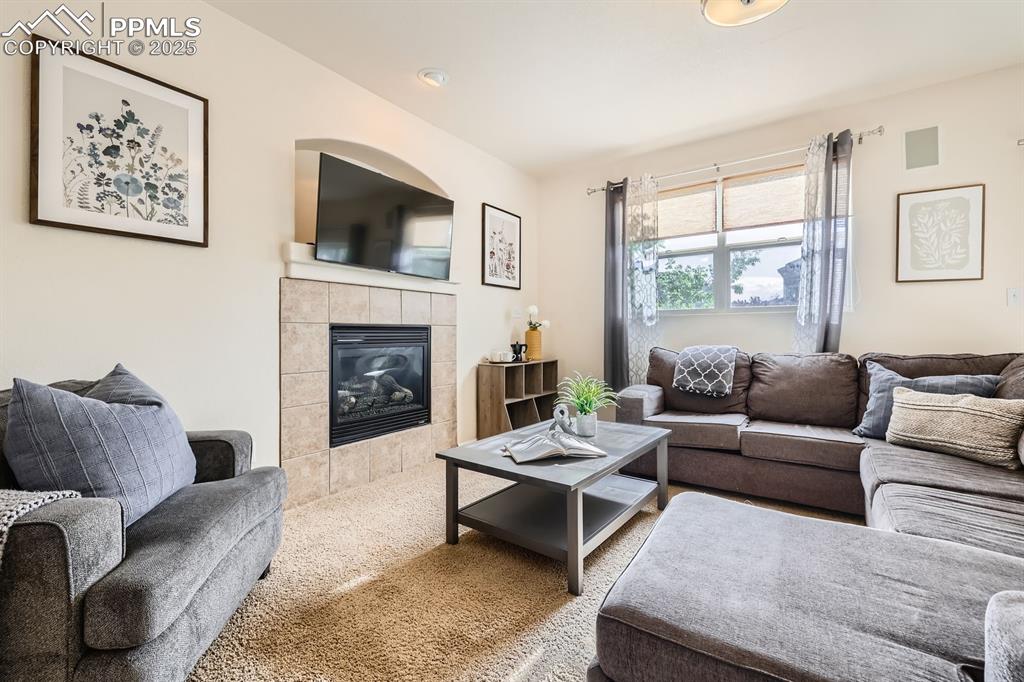 Image 6 of 39: Carpeted living area featuring a tile fireplace