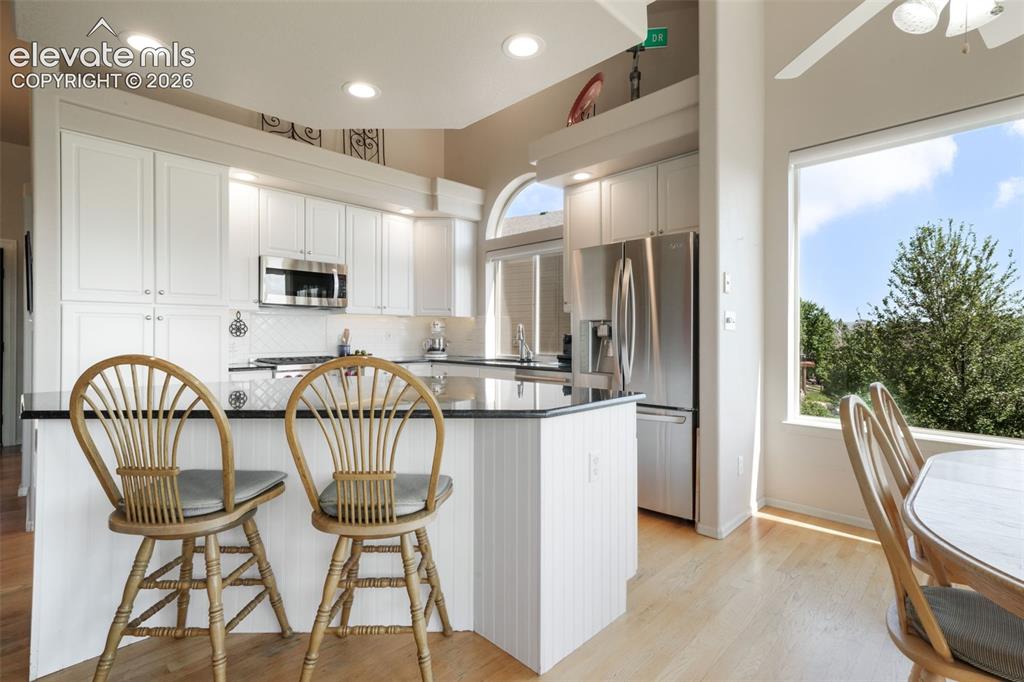 Image 11 of 50: Kitchen featuring white cabinetry, a central island with a dark countertop,