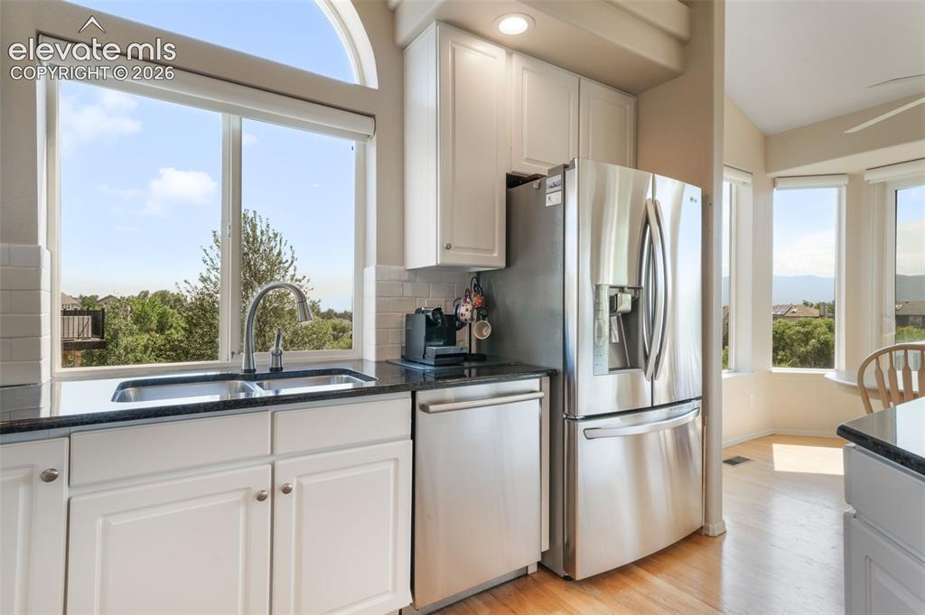Image 12 of 50: Open-concept kitchen featuring white cabinetry, stainless steel appliances,