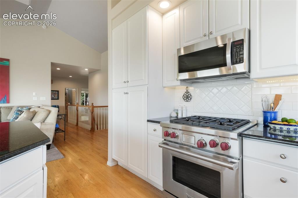 Image 13 of 50: Open-concept kitchen and dining area featuring light wood-finish flooring,