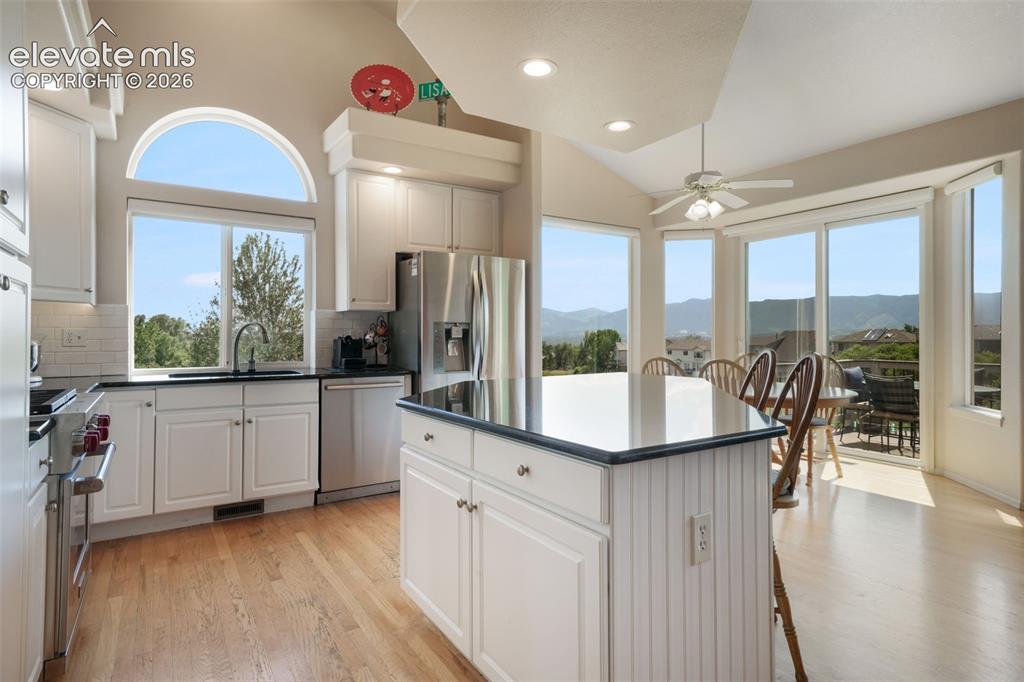 Image 14 of 50: Kitchen featuring white cabinetry, stainless steel appliances, black counte