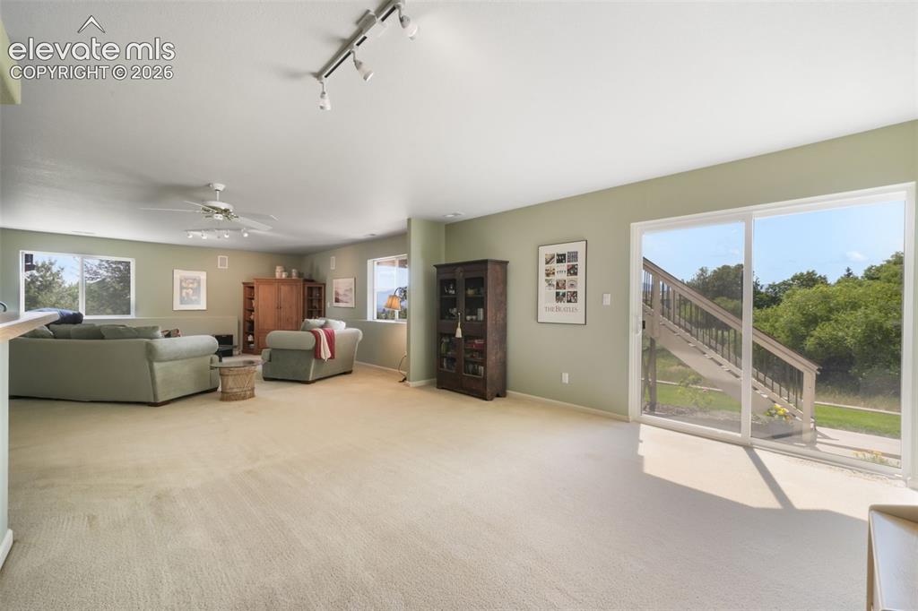 Image 31 of 50: Open-concept hallway with tile flooring, featuring access to a carpeted roo