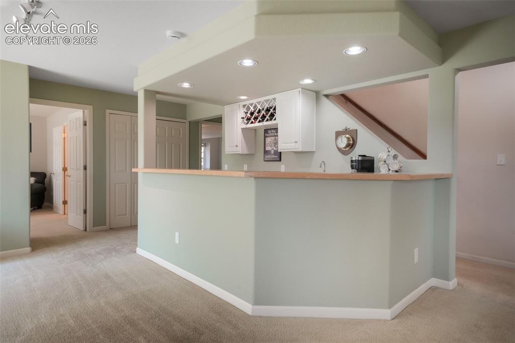 Image 32 of 50: Spacious interior room featuring light-colored carpeting, multiple windows,
