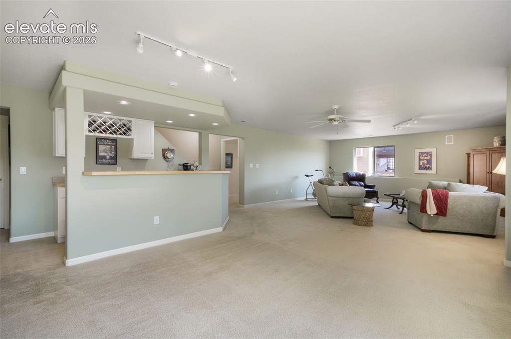 Image 33 of 50: Expansive living area featuring light-colored carpeting and pale green wall