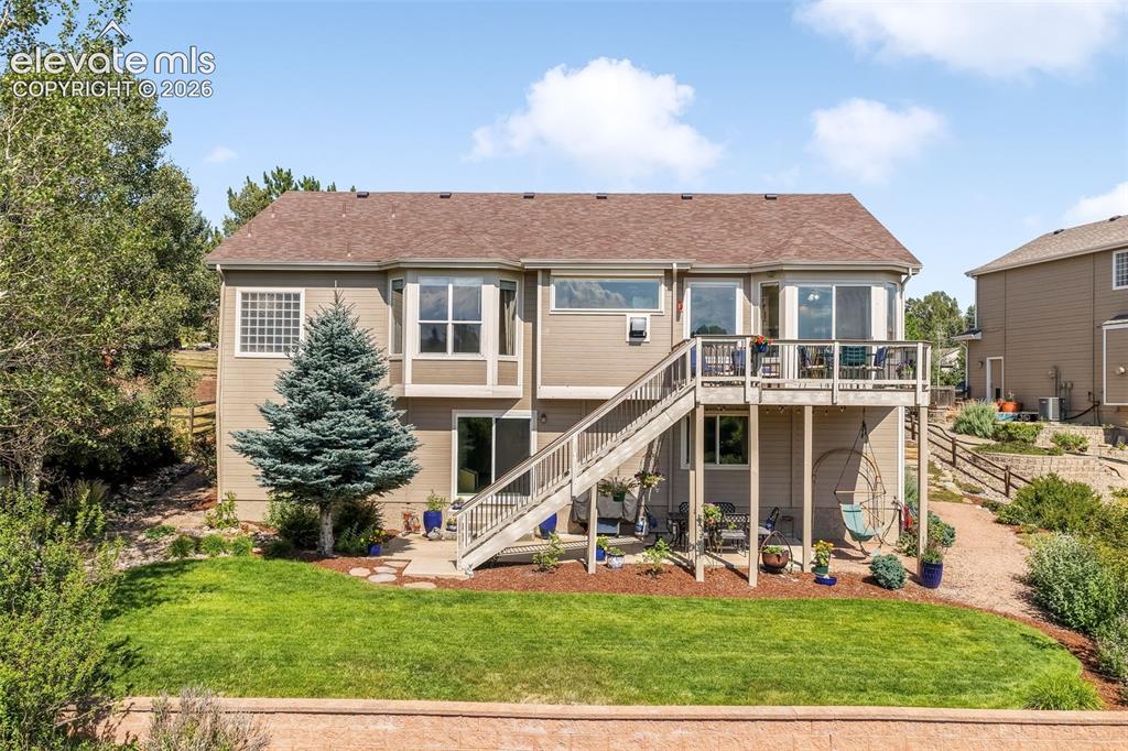 Image 46 of 50: Rear exterior with a multi-level wood deck and stairs, a manicured lawn, an