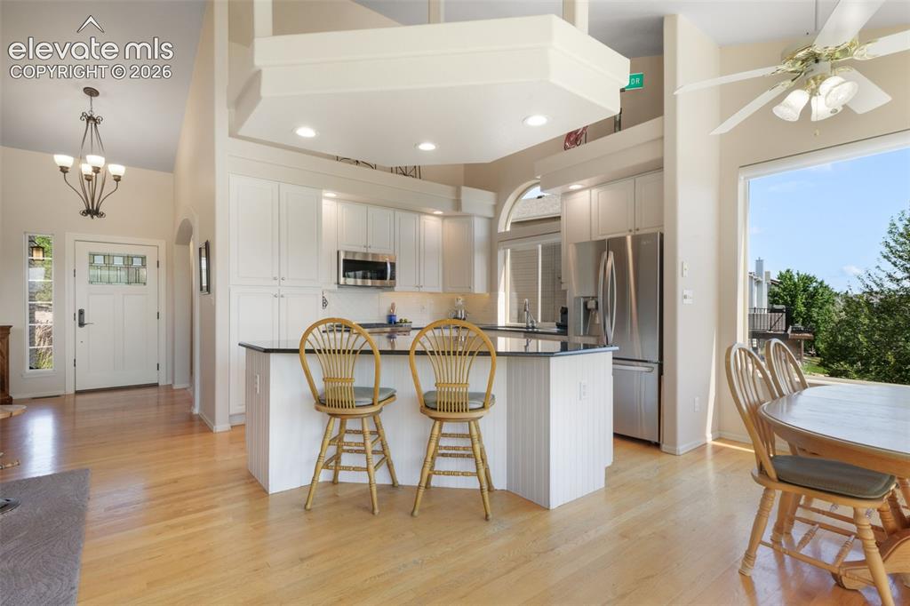 Image 9 of 50: Living area featuring vaulted ceilings, a ceiling fan, and a built-in firep