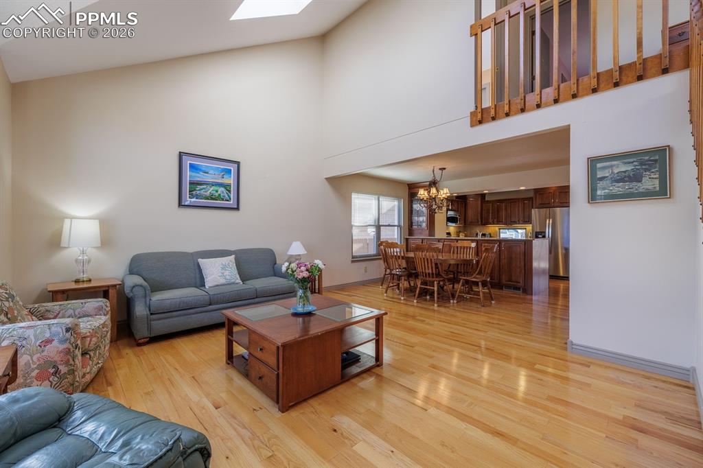 Image 4 of 40: Sunlit living room off the foyer with two skylights and wood flooring