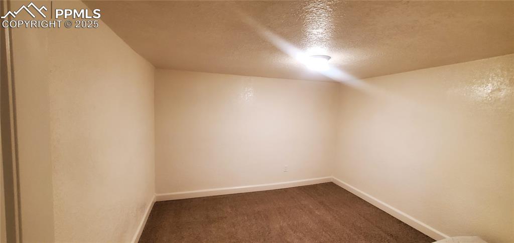 Image 10 of 22: Bonus room featuring a textured ceiling, dark carpet, and baseboards