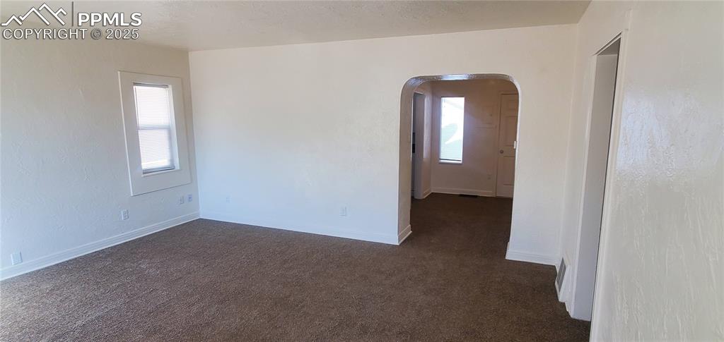 Image 5 of 22: Unfurnished room with dark carpet, plenty of natural light, arched walkways