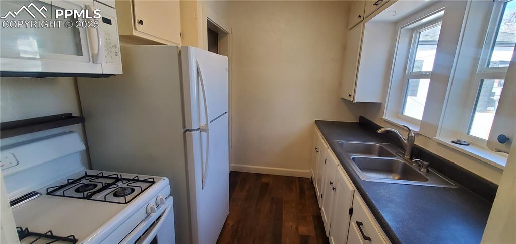 Image 7 of 22: Kitchen featuring white appliances, white cabinets, and dark wood-type floo