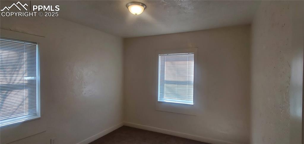 Image 8 of 22: Unfurnished room featuring baseboards and dark carpet