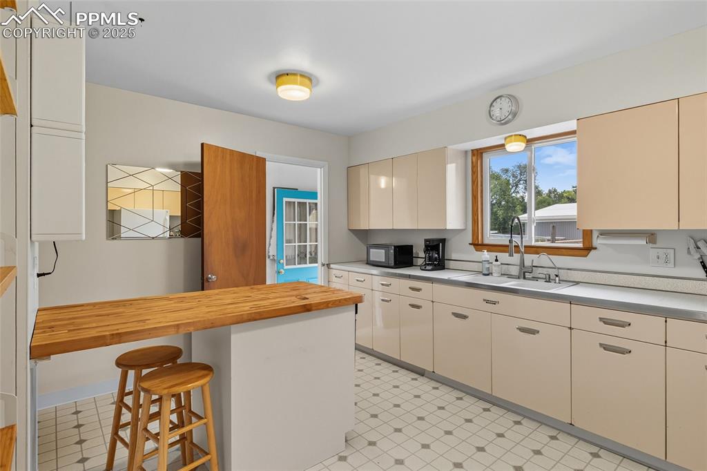 Image 11 of 39: Kitchen with a breakfast bar, butcher block countertops, cream cabinets, bl