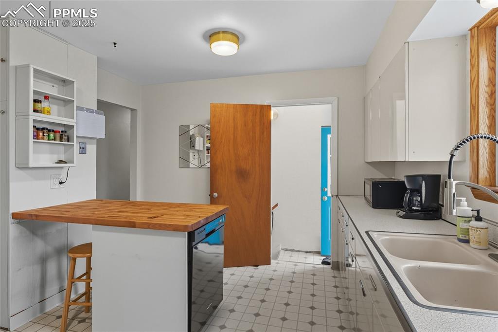 Image 12 of 39: Kitchen featuring white cabinetry, a kitchen bar, butcher block countertops