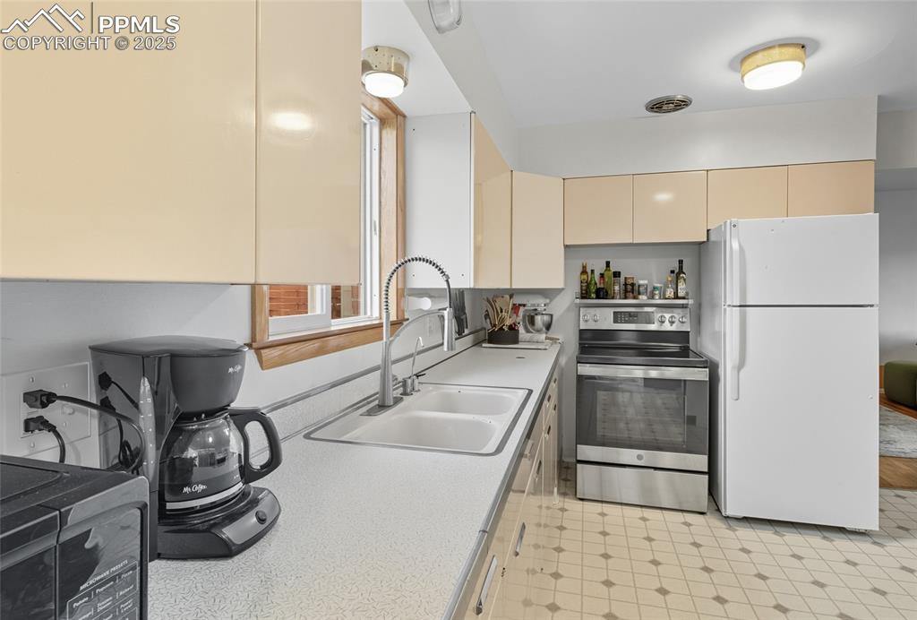 Image 13 of 39: Kitchen with freestanding refrigerator, stainless steel range with electric