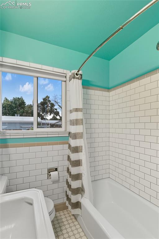 Image 19 of 39: Full bath featuring shower / bath combination with curtain, tile walls, and