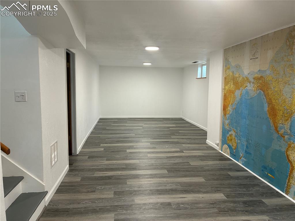 Image 23 of 39: Below grade area with out furniture featuring gray wood-type laminate floor