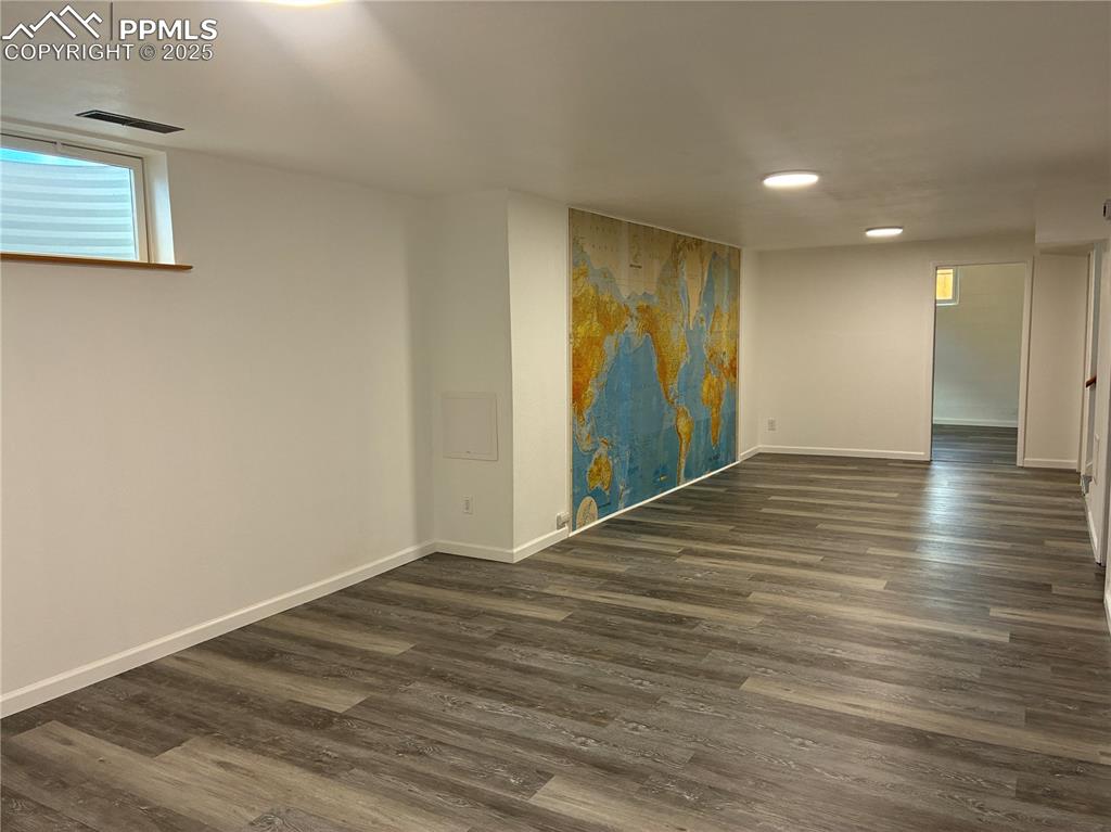 Image 26 of 39: Below grade area with gray laminate wood-style flooring and baseboards