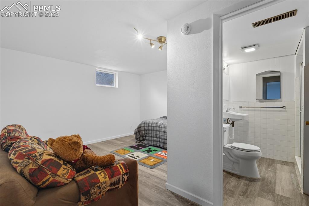 Image 27 of 39: Basement bedroom with a Bathroom featuring laminate wood flooring, tile wal