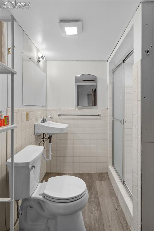 Image 29 of 39: Bathroom with tile walls, light wood finished floors, and a stall shower